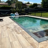 Dalle effet bois 30*120 avec margelles de piscine anthracite et piscine en pierre de bali