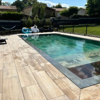 Dalle effet bois 30*120 avec margelles de piscine anthracite et piscine en pierre de bali