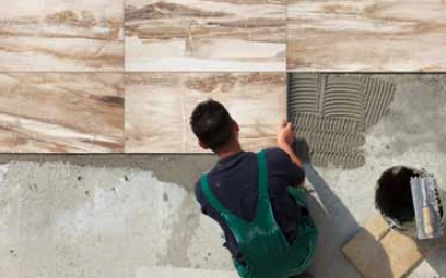 Un homme en train de collé des dalles avec de la colle